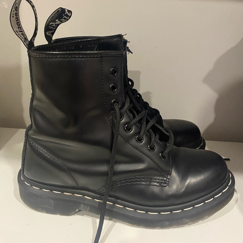 Dr. Martins black leather boots with white stitching.